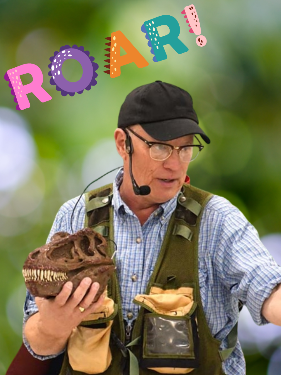 A man wearing a plaid button-up shirt, a green utility vest, and a black baseball cap speaks into a headset while holding a dinosaur skull.
