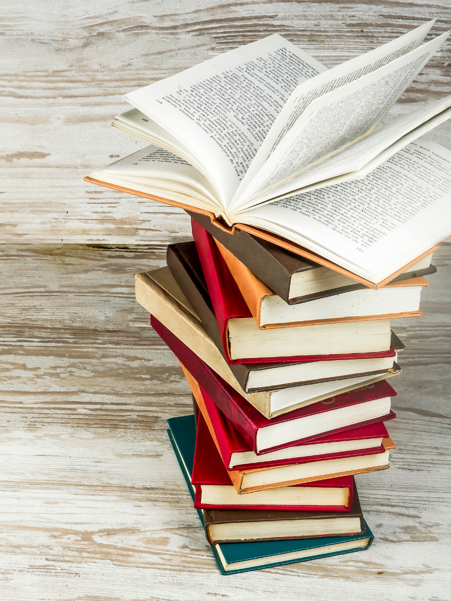 stack of books on distressed white wooden planks