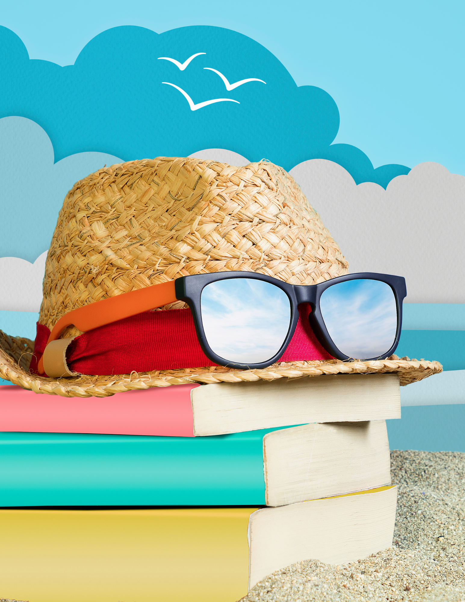 Straw fedora with sunglass sitting atop a stack of colorful books on a sandy beach