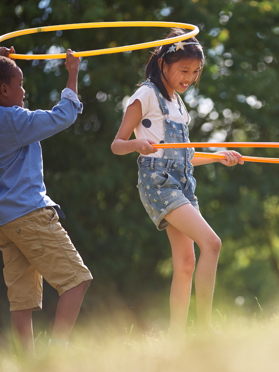 Kids play with hula hoops in the sunshine.