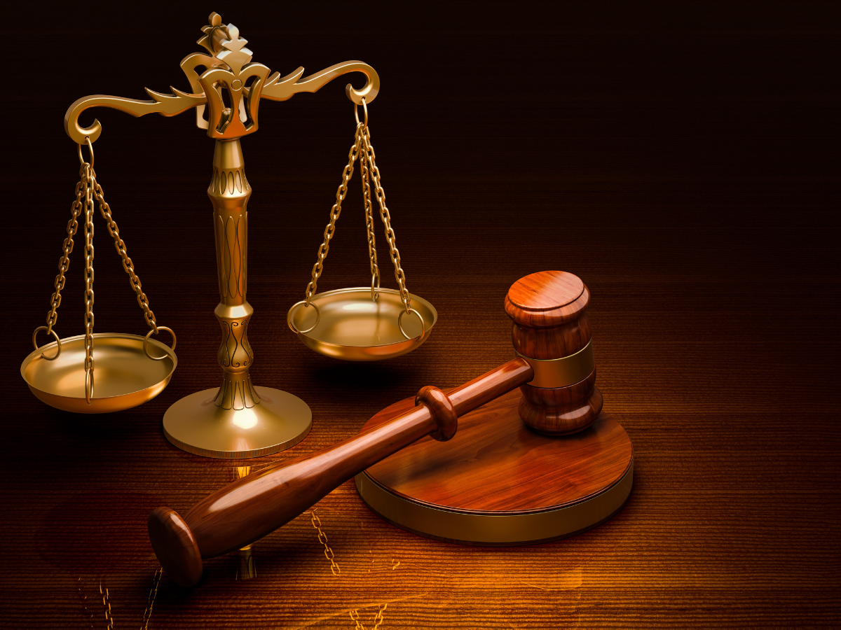 Gold scales and a wooden gavel on a wooden tabletop