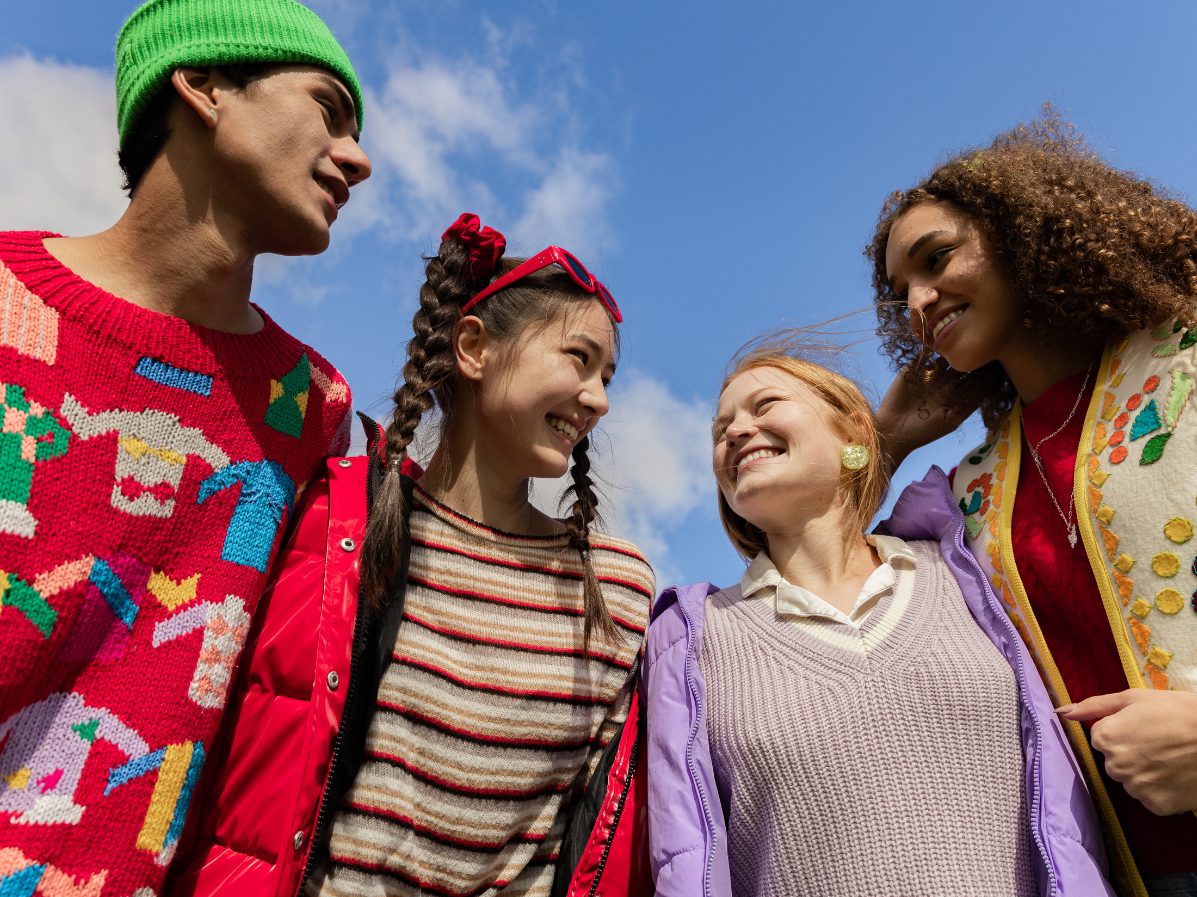 Teens in a group with a blue sky in the background.