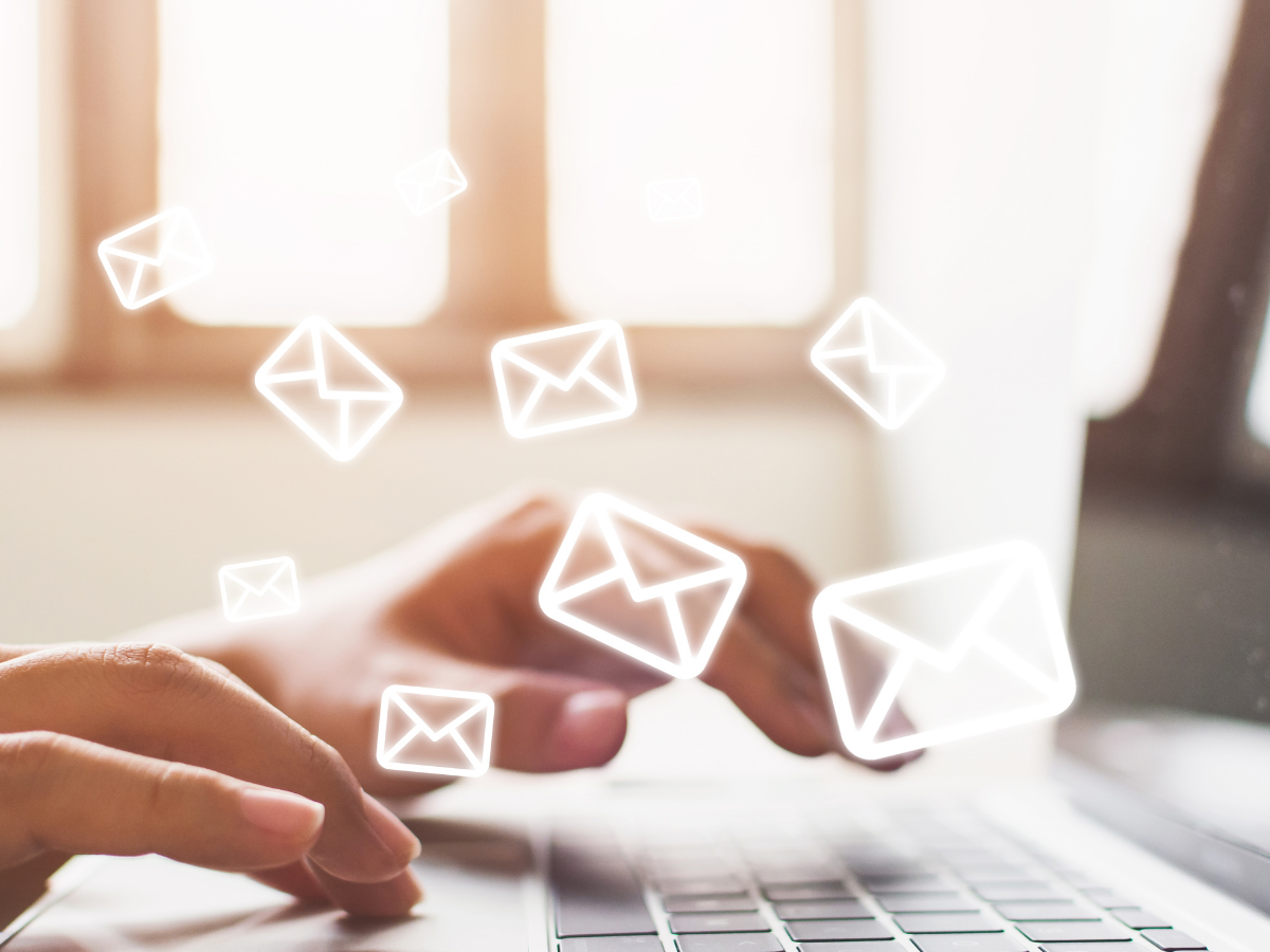 Hands typing on a laptop with several envelope emojis  laid over the image.